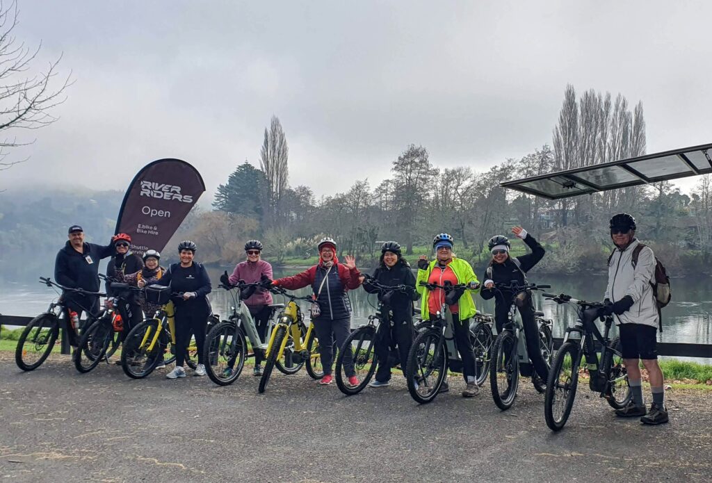 Group of people standing with their bikes with the Waikato River in the background