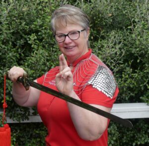 Smiling woman in a red shirt with a sword